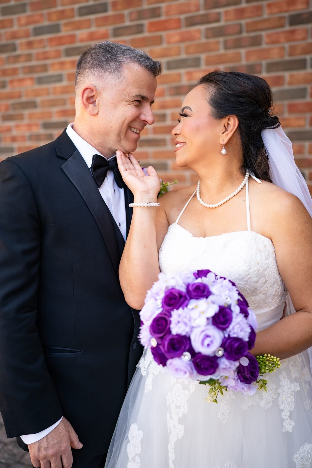 Bride and groom laughing against a brick wall on their Windsor wedding day