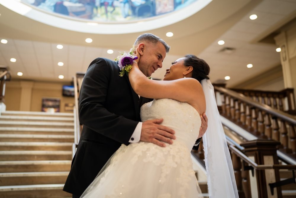 Bride and groom embracing beneath the painted skylight at the Giovanni Caboto Club in Windsor, Ontario